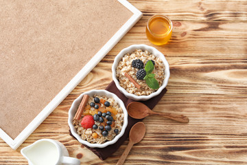 Tasty oatmeal with berries in bowls on table