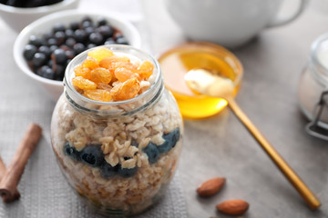 Tasty oatmeal with raisins in jar on table