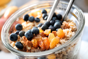Nutritious oatmeal with raisins and blueberry in glass, close up