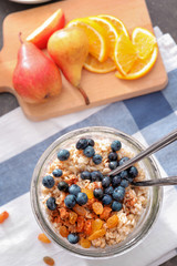 Nutritious oatmeal with raisins and blueberry in glass on table
