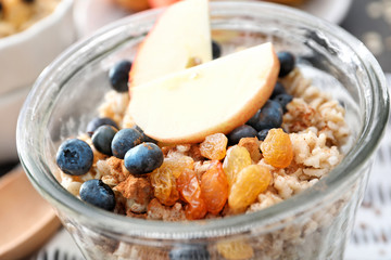 Tasty oatmeal with fruit and berries in glass on table, close up