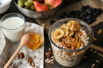 Nutritious oatmeal with banana and raisins in glass on table