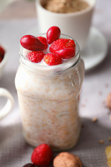 Nutritious oatmeal with berries and milk in jar on table