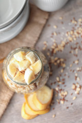 Nutritious oatmeal with banana in jar on table
