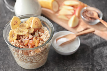 Nutritious oatmeal with banana and raisins in glass on table