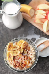 Nutritious oatmeal with banana and raisins in glass on table