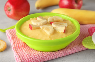 Plastic bowl with porridge for baby on fabric