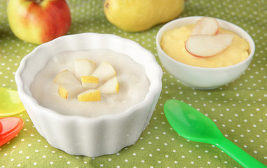 Ceramic bowls with porridge for baby on fabric