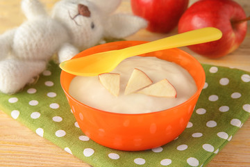 Plastic bowl with porridge for baby on fabric