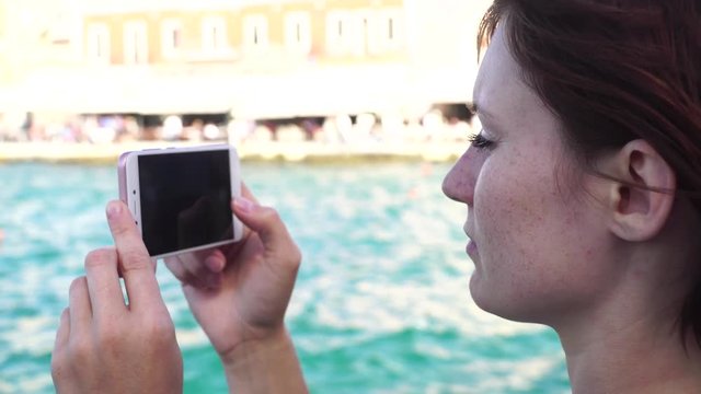 Young woman takes the photo a lighthouse in a European city uses smartphone