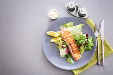Plate with slice of delicious salmon on table