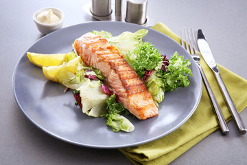 Plate with slice of delicious salmon on table