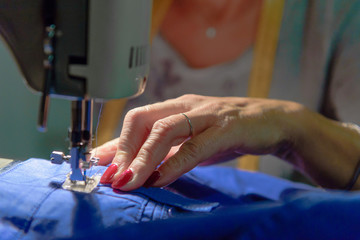 Close up on sewing machine and seamstress' hand while she is working