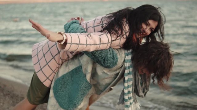 two young attractive girls have fun and embrace. best friends spend time together outdoors by the water. portrait of girlfriends on the beach at sunset