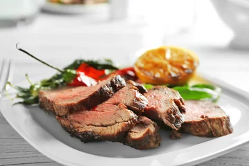 Deurstickers Steakhouse Plate with sliced delicious steak and vegetables on table