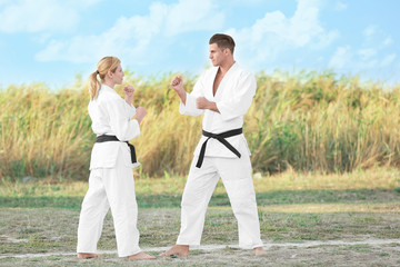 Young man and woman practicing karate outdoors