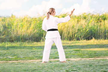 Young woman practicing karate outdoors