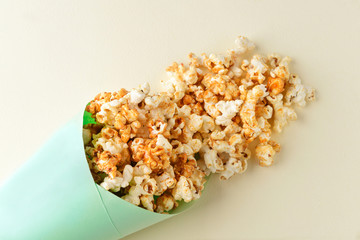 Paper cone with tasty caramel popcorn on light background