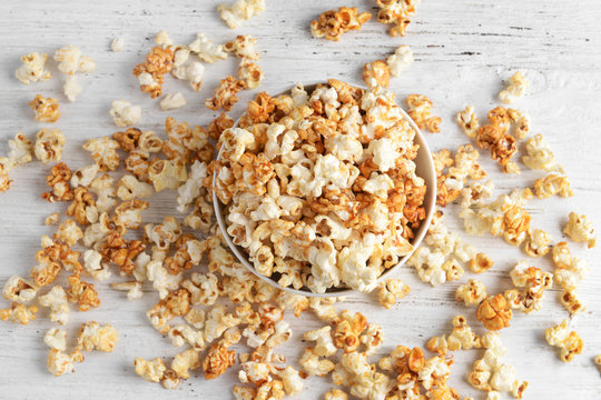 Bowl with tasty caramel popcorn on wooden background