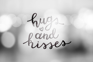 hugs and kisses, lettering, vector handwritten text on blurred lights