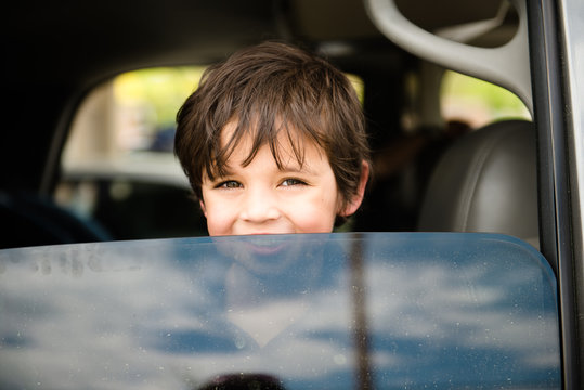 Smiling Boy Looks Out An Open Car Window