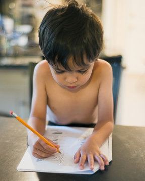 little boy doing homework with a pencil