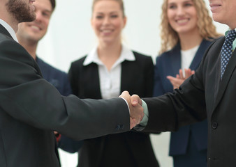Mature businessman shaking hand of  his partner with colleagues 