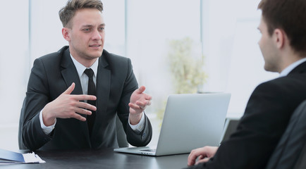 Fototapeta premium Bank employee sitting behind a Desk and talks to the client