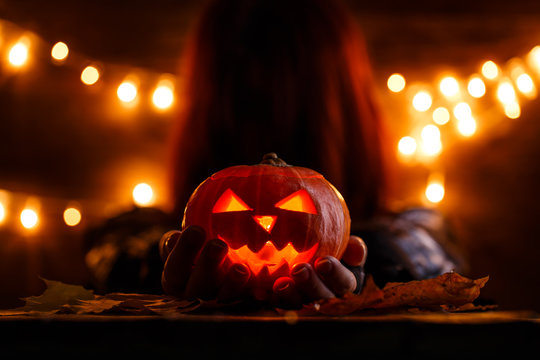Photo of witch with long hair holding halloween pumpkin