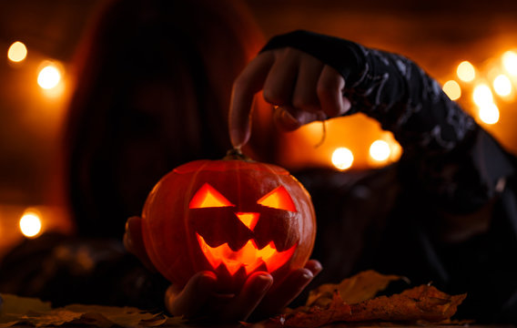Picture of witch with long hair showing hand on halloween pumpkin
