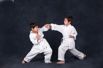 two boys of the karateka in a white kimono battle or train