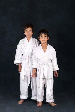 two boys of the karateka in a white kimono stand and smile