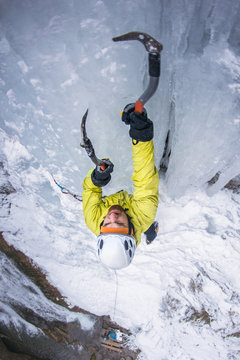 Athlete ice climbing frozen waterfall