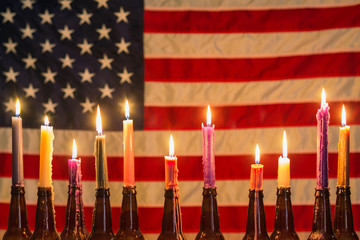 American flag illuminated by a row of candles in beer bottle holders