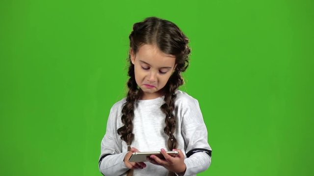 Child thumbs the photo on the phone. Green screen. Slow motion