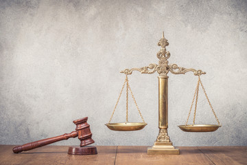 Vintage law scales and wooden gavel on table. Symbols of justice. Retro old style filtered photo