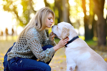blonde playing with her labrador in autumn park