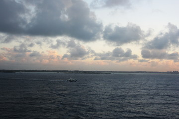 Arial view of a boat sailing on the ocean with the coast on the horizon on a cloudy day