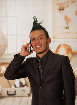 Close up of happy office punk worker wearing a suit with a crest, using his cellphone in the office in a blurred background