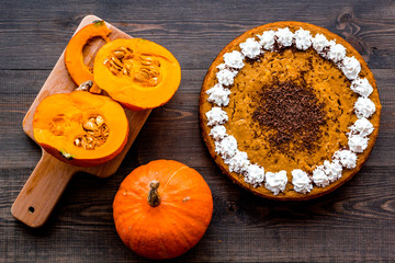 Make pumpkin pie. Whole cake near pumpkins on wooden background top view