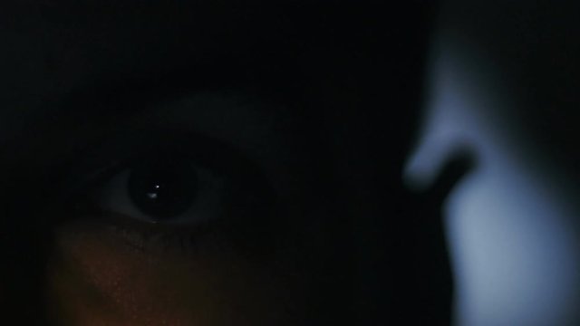 extreme close-up of young man watching a movie at night. Reflection on the face