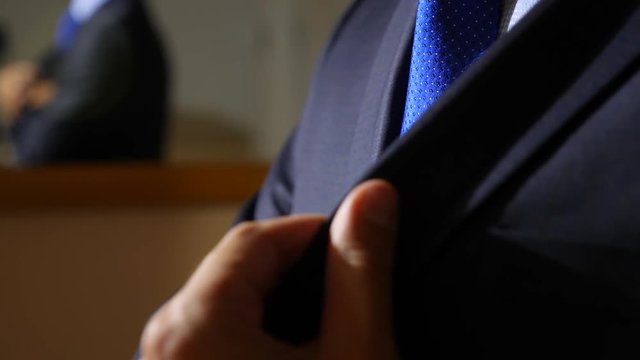 An unrecognizable businessman, puts the phone in the inner pocket of his jacket. 4k, slow motion