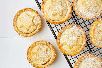 Traditional British Christmas Pastry Dessert Home Baked Mince Pies with Apple Raisins Nuts Filling on Cooling Rack. Golden Shortcrust Powdered. White Plank Wood Table. Festive Setting