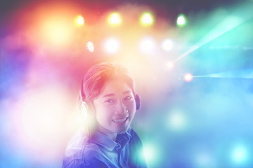 asian pretty woman listening to music in headphones with colorful light background,fun like in party