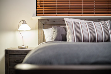 Modern home interior with bedroom setting including bedside table with lamp.