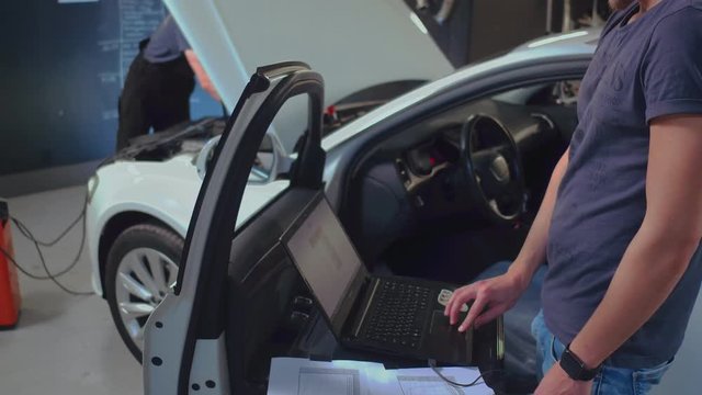 Auto mechanic repairing car in service. Service man making car diagnostic