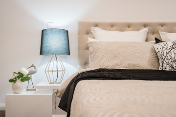 Modern home interior with bedroom setting including bedside table with lamp.