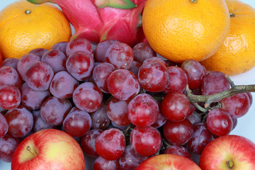 Naklejka na ściany i meble Mixed fruits as Red seedless grapes,orange,apple,Dragon fruit,Japanese golden melon.