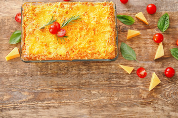 Traditional meat lasagna in baking dish on wooden table