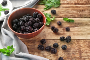 Bowl with delicious ripe blackberries on wooden table